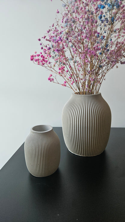 dvi betonines vazos ant juodo paviršiaus baltame fone