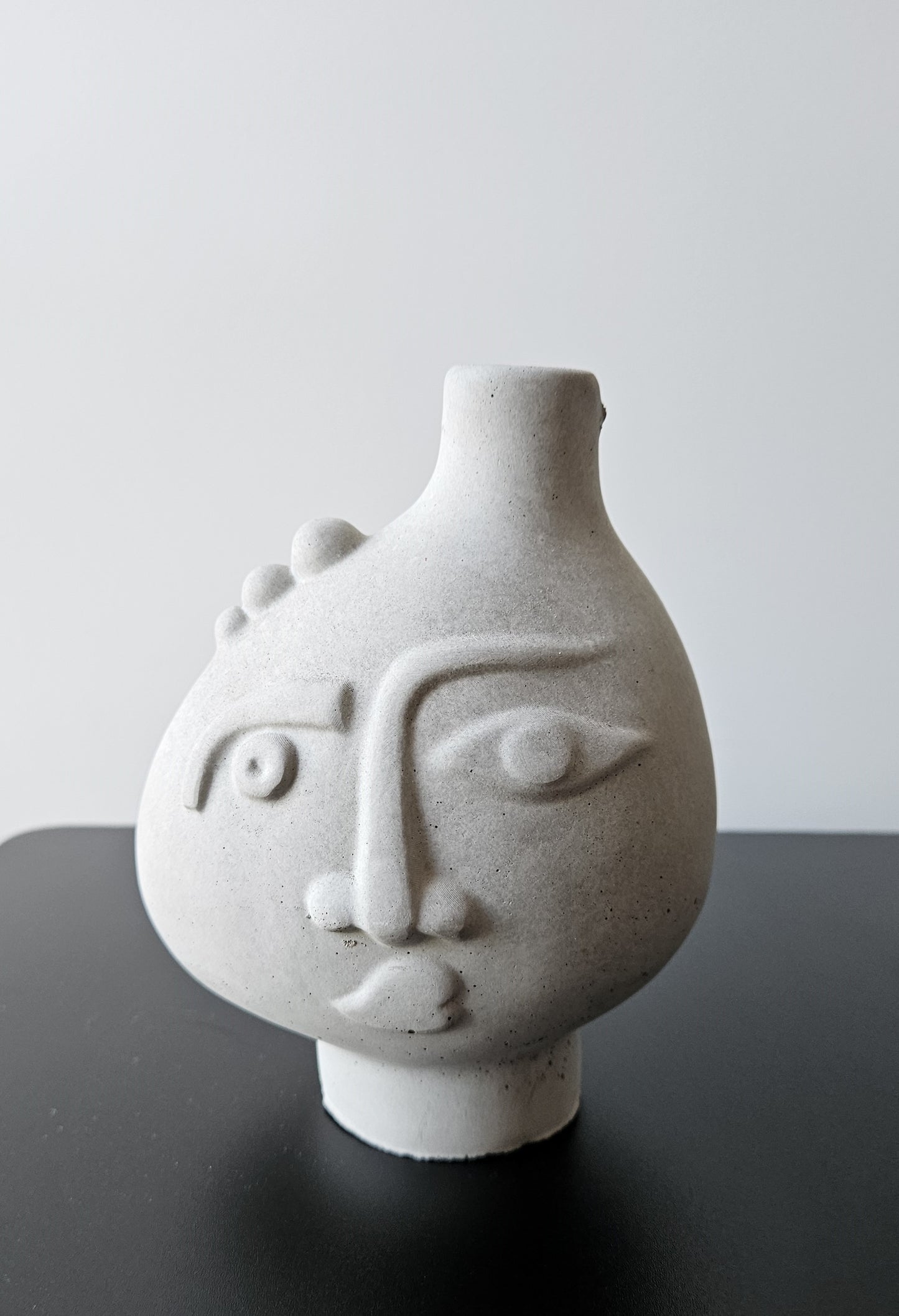 Rankų darbo betoninė vazelė su žmogaus veido reljefu ir sausomis gėlėmis – minimalistinė interjero detalė, tinkanti moderniam ir wabi-sabi stiliaus namų dekorui