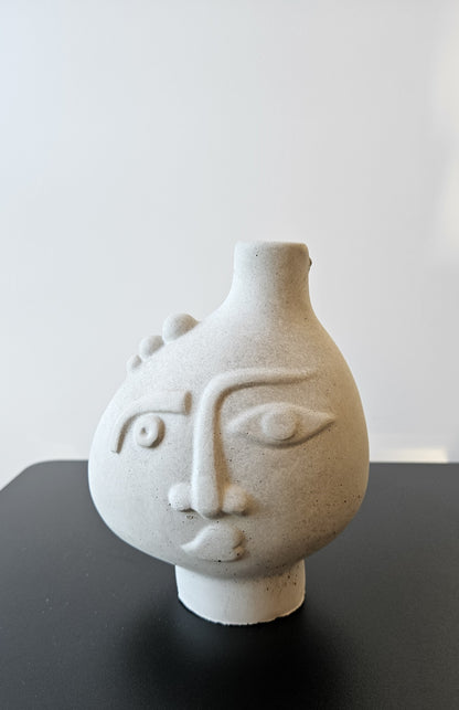 Rankų darbo betoninė vazelė su žmogaus veido reljefu ir sausomis gėlėmis – minimalistinė interjero detalė, tinkanti moderniam ir wabi-sabi stiliaus namų dekorui