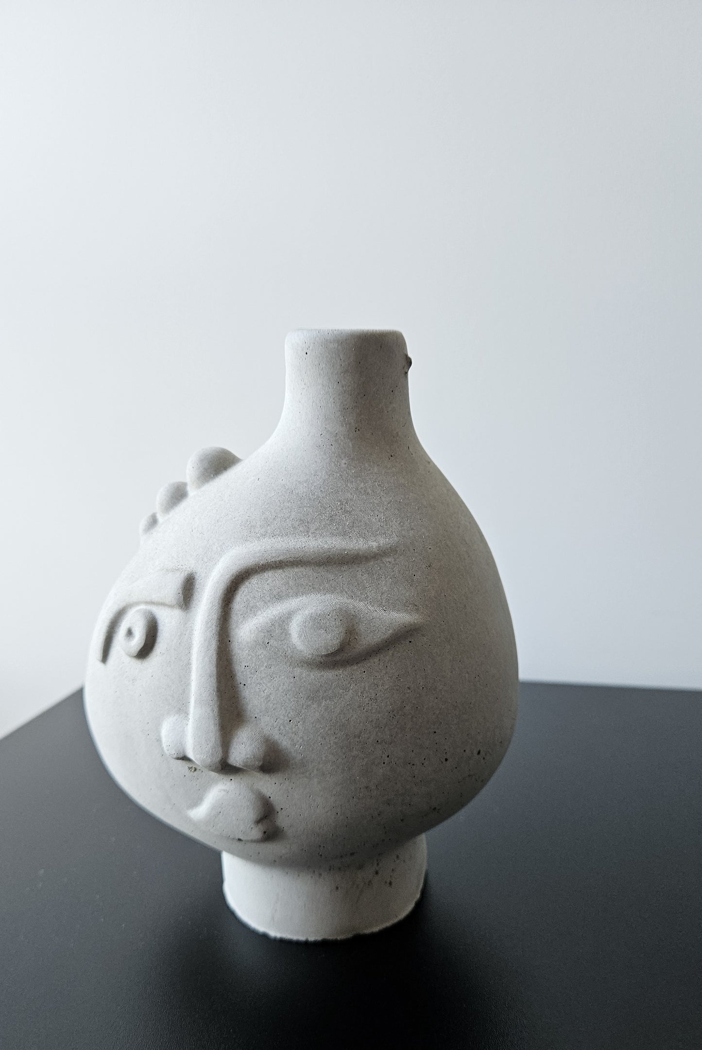 Rankų darbo betoninė vazelė su žmogaus veido reljefu ir sausomis gėlėmis – minimalistinė interjero detalė, tinkanti moderniam ir wabi-sabi stiliaus namų dekorui