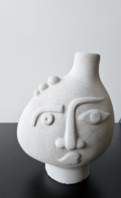 Rankų darbo betoninė vazelė su žmogaus veido reljefu ir sausomis gėlėmis – minimalistinė interjero detalė, tinkanti moderniam ir wabi-sabi stiliaus namų dekorui