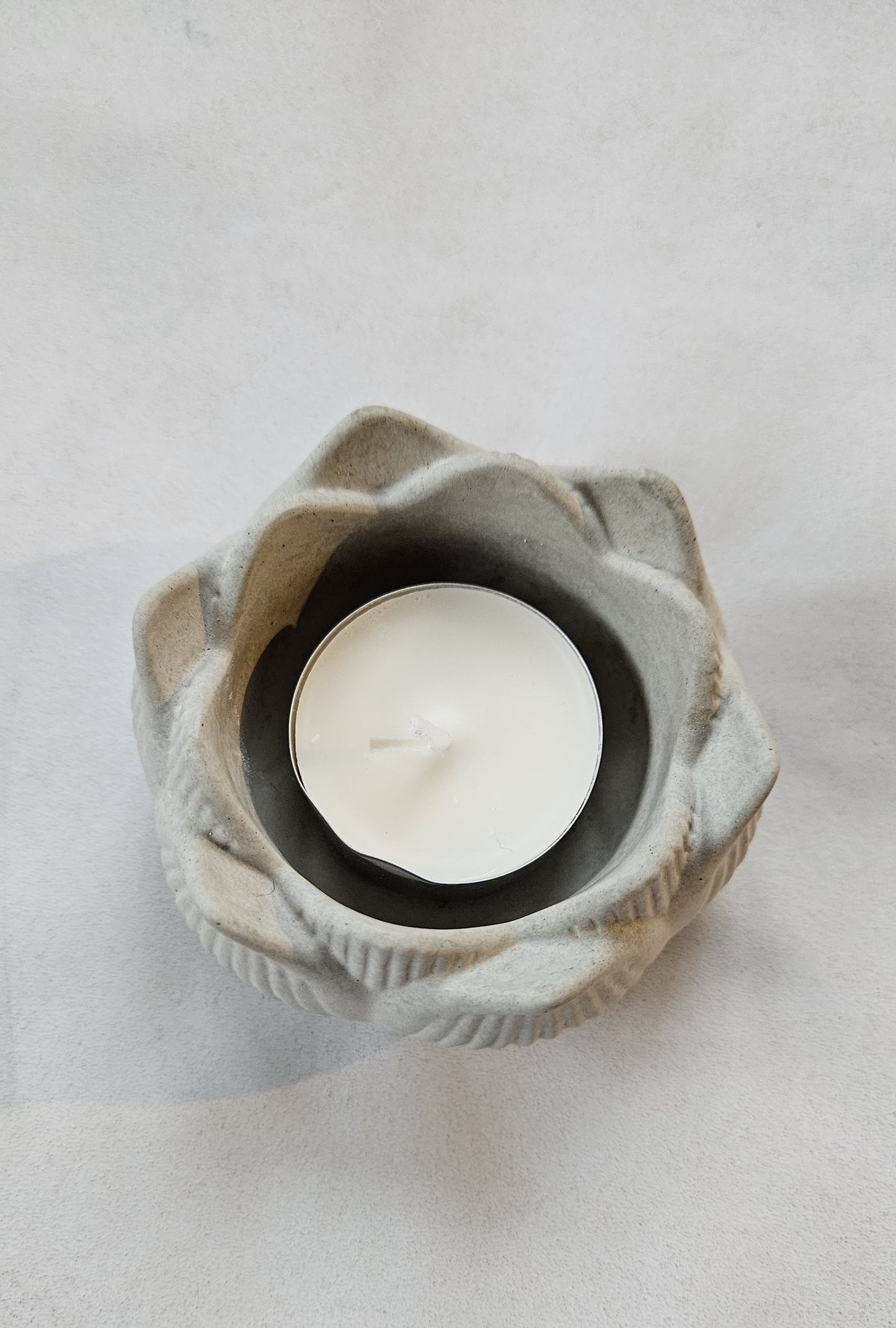 pilka betoninė žvakidė lotosas ant pilko fono