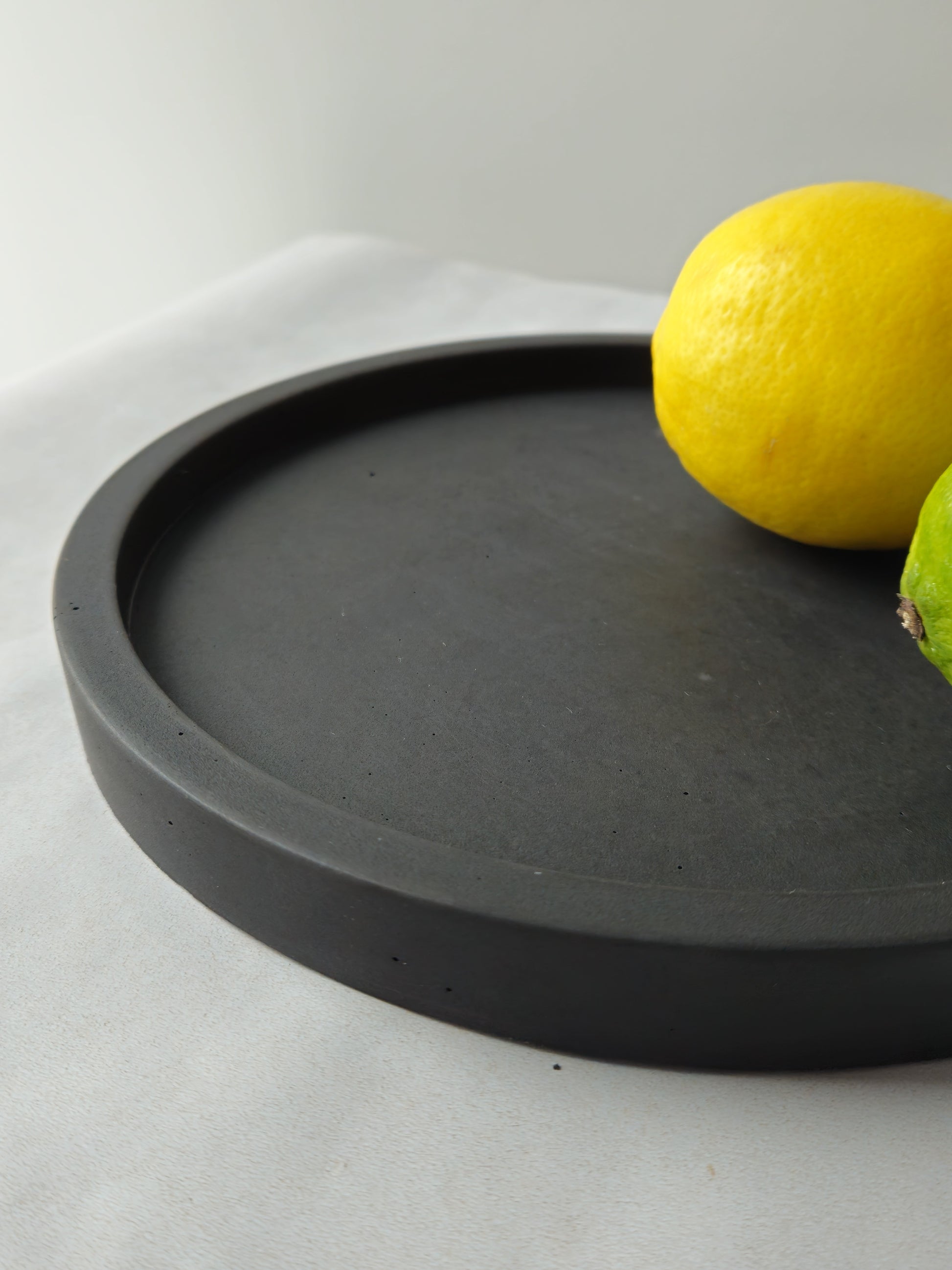 juodas betoninis padėklas su citrina ir laimu