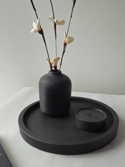 juodas betoninis padėklas su vazele ir smilkaline