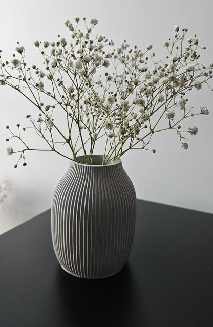 natūralaus betono spalvos vazelė banguotu paviršiumi industriniam interjerui